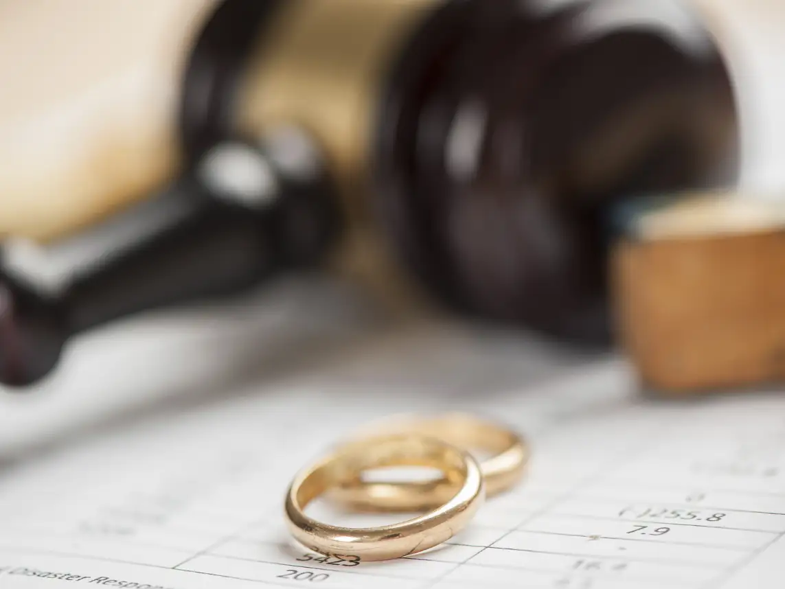 Two wedding rings laying on a contract by a court gavel 